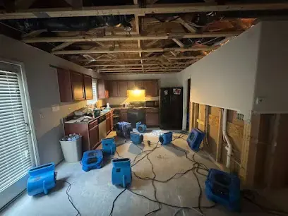 Kitchen and family room with the lower walls opened, the ceiling cut back and blue air movers drying the floor