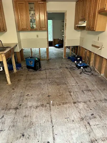 Kitchen with the flooring pulled up and air movers drying along the base cabinets