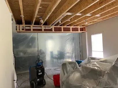 Room sealed off with plastic containment, a dehumidifier and an air mover during a water damage dry-out