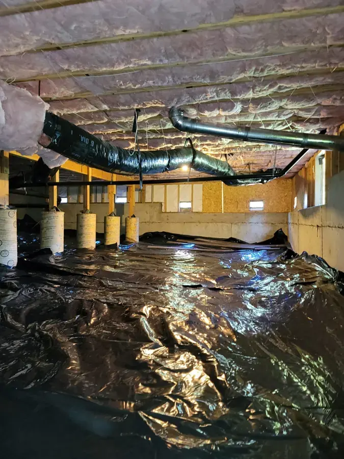 Water pooled on the plastic ground cover of a crawl space under sagging floor insulation